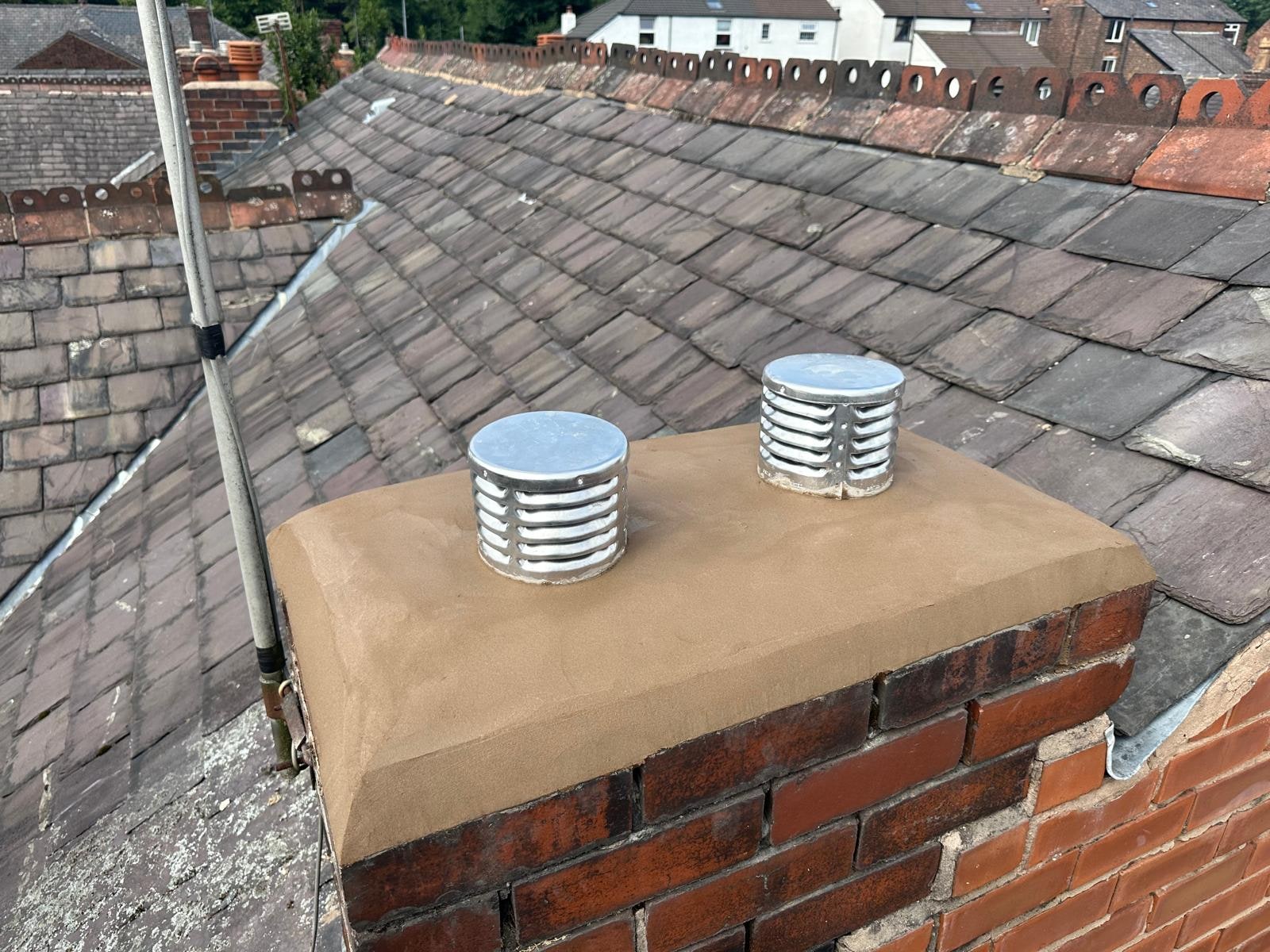 A brick chimney with fresh flaunching and two vented cowls