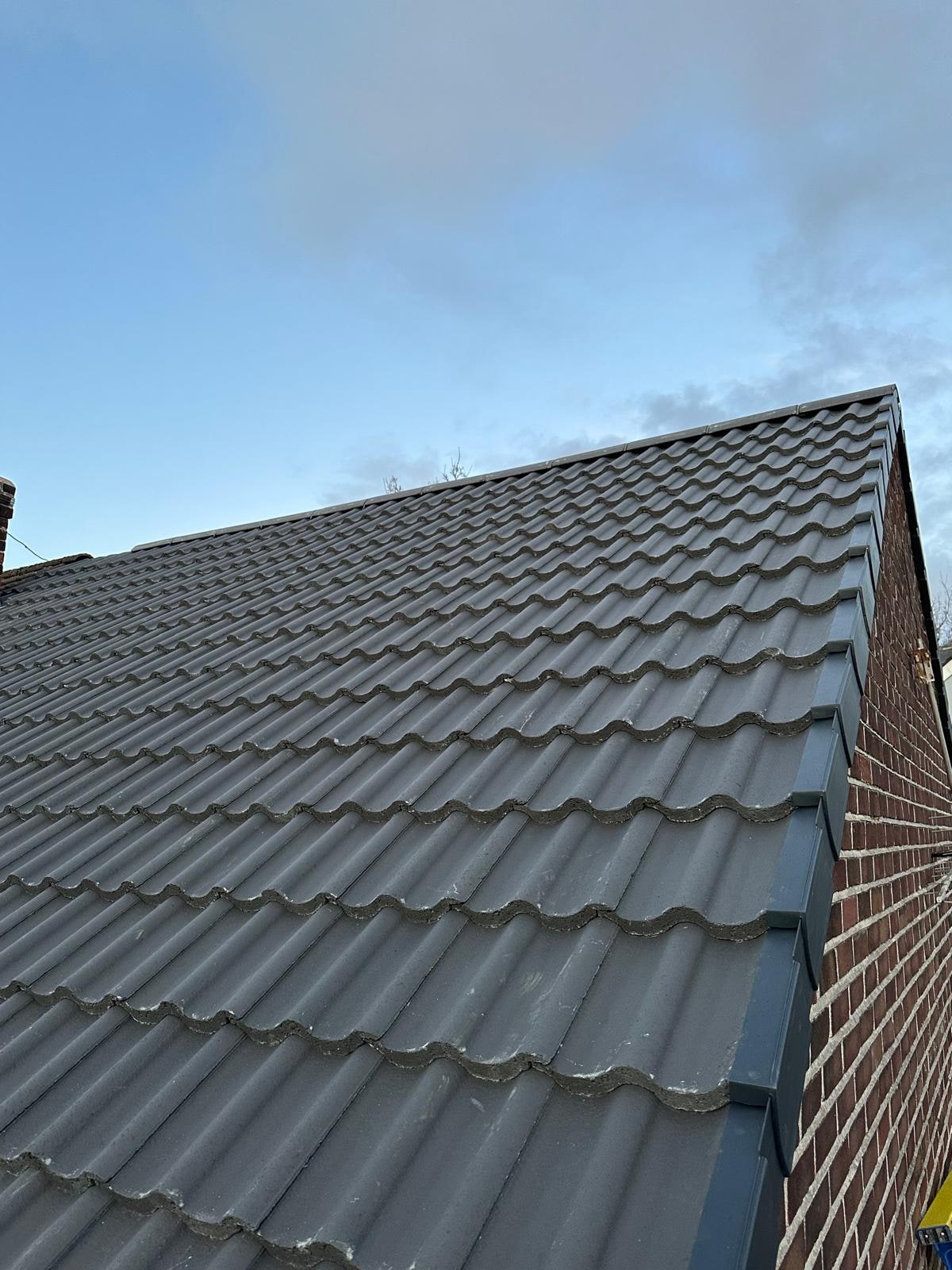 Finished grey pantiles with a mortared verge in evening light